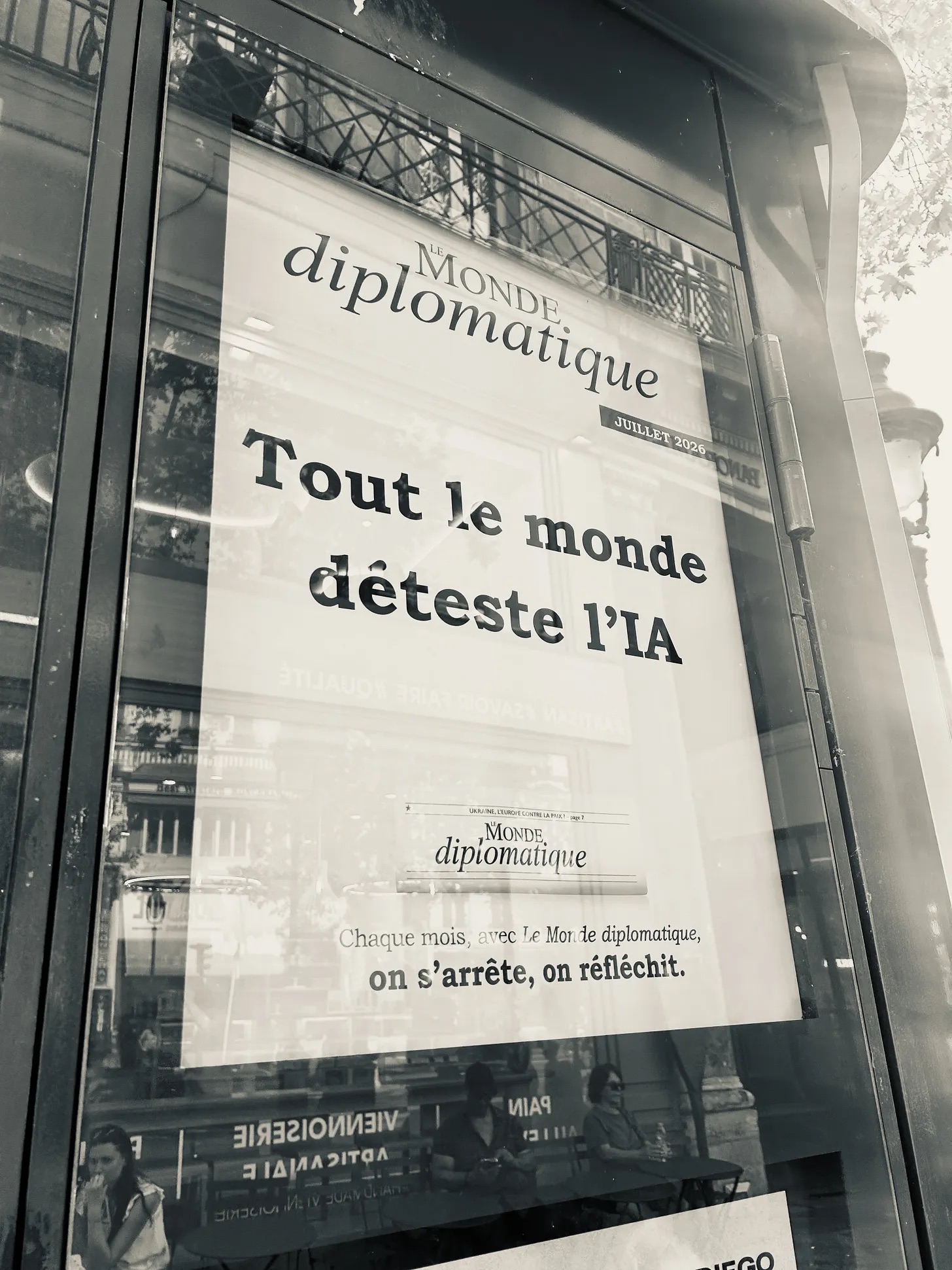 A sepia photo of a poster on a Parisian kiosk. It is an ad for Le Monde diplomatique and has the headline “Tout le monde déteste l’IA"